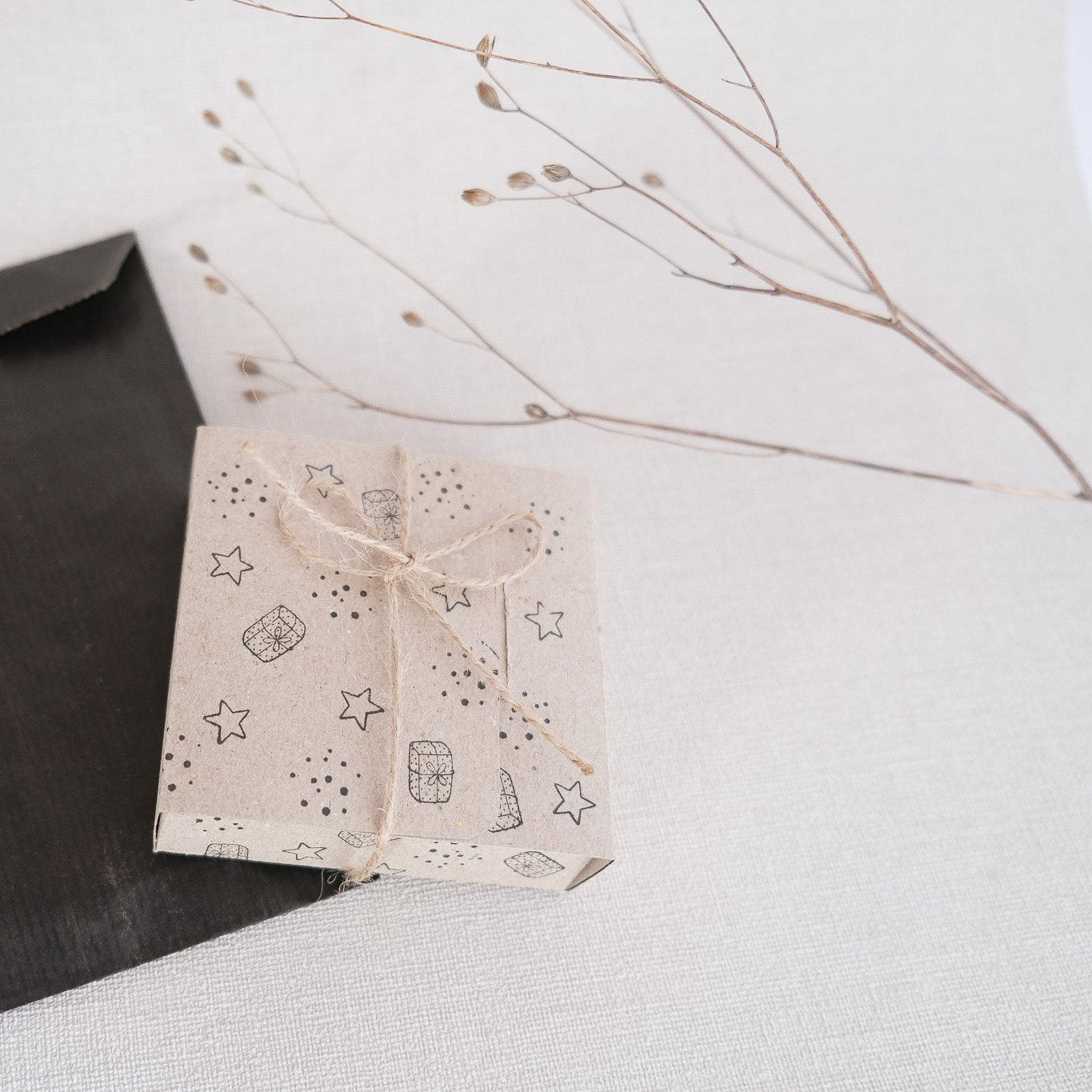 Bastelbeispiel Geschenkbox aus Kraftpapier bestempelt mit Sternen, Punkten und Geschenken.